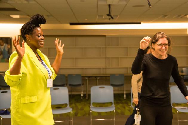 Two women are laughing with their hands raised 