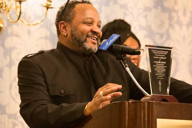 A man standing at the podium is addressing the crowd and smiling. 