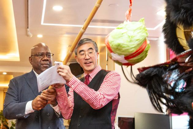 Retired UFT Secretary and Staff Director LeRoy Barr (left), who was honored at the event, and Asian American Heritage Committee Chair Seung Lee carry on the tradition of feeding lettuce to the lion, symbolizing good fortune.