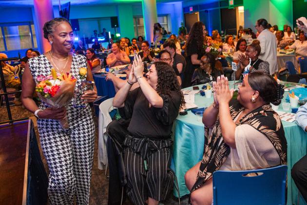 Community Champion honoree Cassandra Dozier,  the school secretary at Curtis HS on Staten Island, receives her flowers amid cheers at the 2026 UFT Academic High School Awards