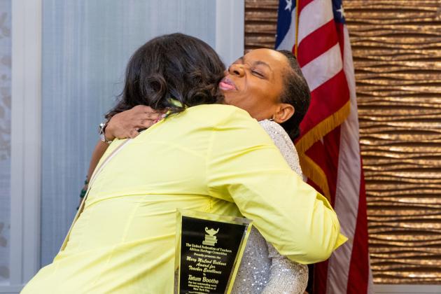Two women share a hug after one of them receives an award. 