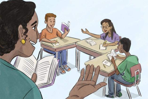 Teacher holding book standing with students at desk following along the book and taking notes