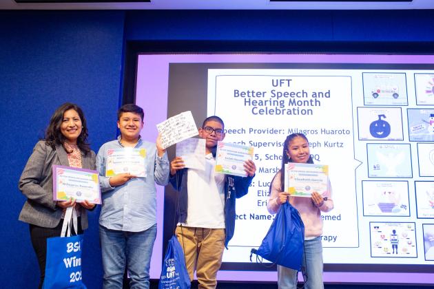 A speech teacher and her students at the UFT Speech Improvement Chapter's Better Speech and Hearing Month celebration show off their certificates they received for a project
