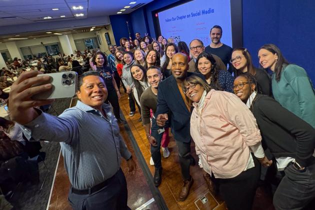 Social Worker and Psychologists Chapter Leader Raul Garcia takes a group selfie with UFT members on stage.