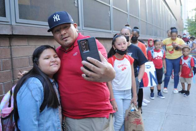 A father and daughter take a selfie outside a school