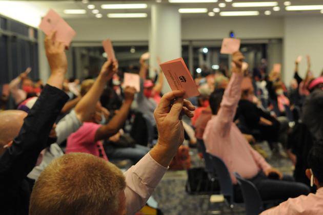 People raising hands with ballots