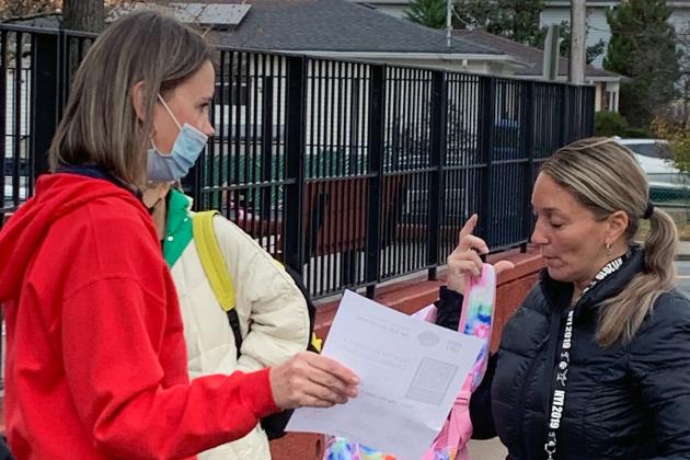 A member hands out fliers to parents outside PS 55 on Staten Island.