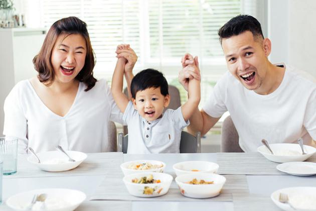 Asian couple with small child smiling with hands up
