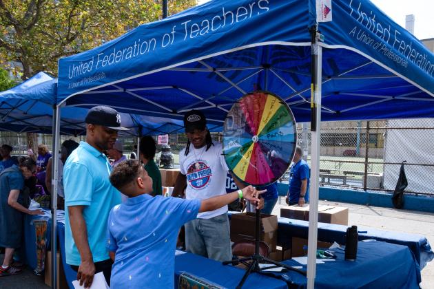 Families line up at the UFT booth during Harlem week festivities.