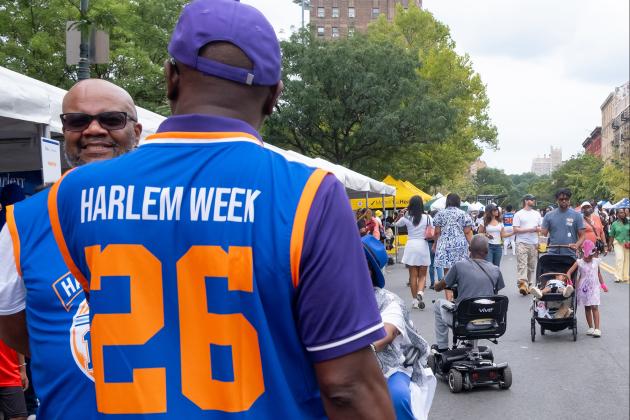 A man wearing a basketball jersey where the back reads "Harlem Week 26". 