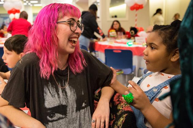 Adult with pink hair laughs