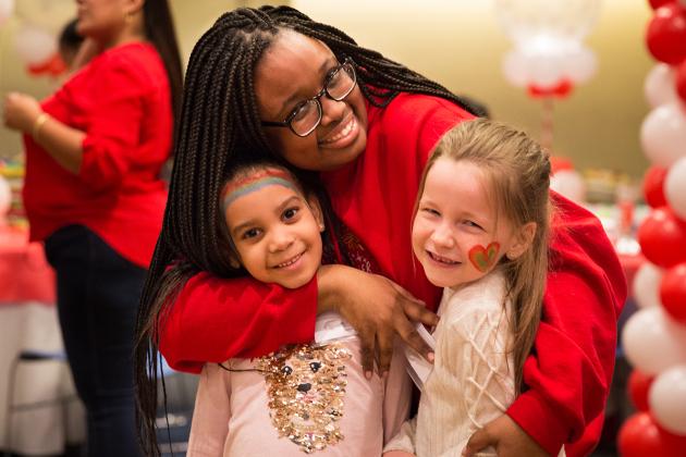 Woman in red hugging two girls