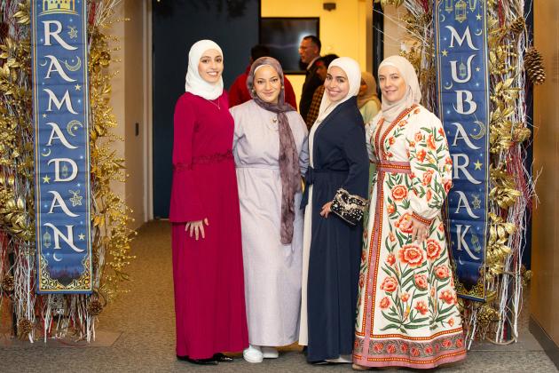 Teachers attending the UFT Muslim Educators Committee Iftar Dinner on March 7, 2025 pose between banners reading “Ramadan Mubarak,” which means “Blessed Ramadan.”