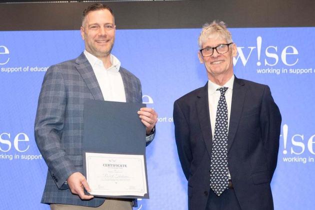Award-winning teacher Robert Trialonas is congratulated by David Anderson, president and CEO of W!se.