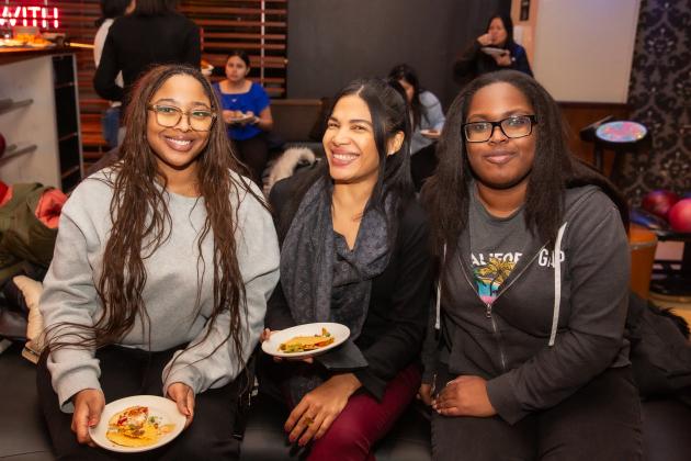 Three women at a new member bowling event for UFT Manhattan members smile for a photo while sitting together. 