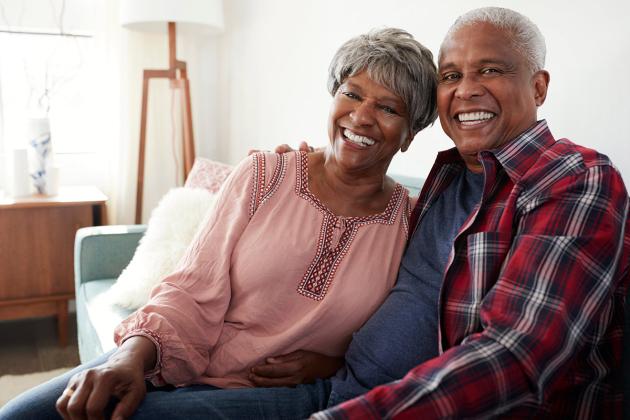 Mature African American Couple sitting on a couch smiling