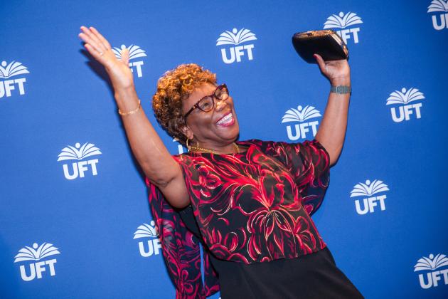 A new retiree takes a photo in front of the UFT backdrop at the UFT New Retiree Luncheon at the Midtown Hilton on Dec. 5, 2024
