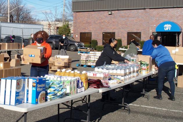 Woman carrying boxes while other people load them