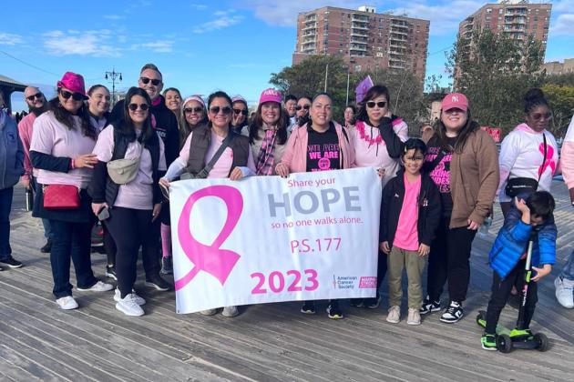 A group of marchers working in Brooklyn pose for a group photo during a breast cancer awareness march.