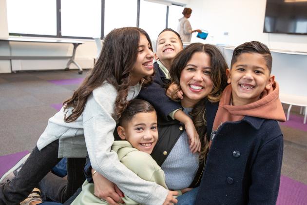 A parent in attendance takes a photo with her children at the UFT Queens Parent Summit on Nov. 23, 2024