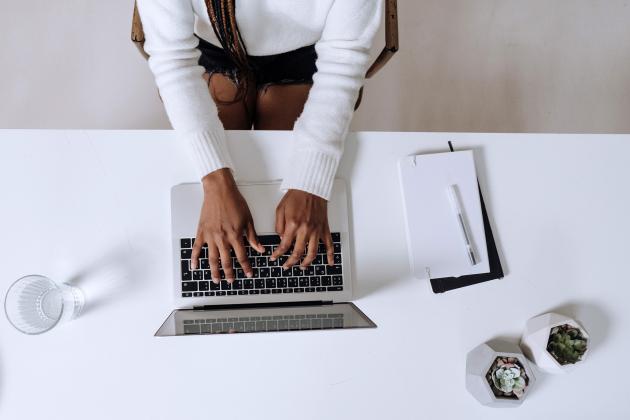 Woman sitting at a desk typing on a laptop keyboard