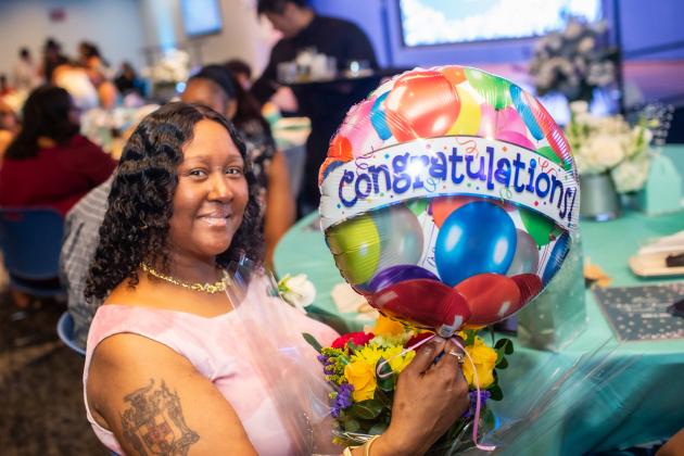 School secretary Glenda Cummings of PS/IS 155 in Brooklyn, one of 30 School Secretary of the Year honorees, smiles with her congratulatory gift in hand at the UFT School Secretary Awards Soiree on June 6, 2025. 