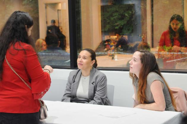 A woman talks to two social workers at a table.