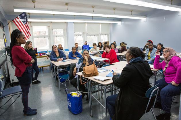 People seated in a classroom with teacher standing
