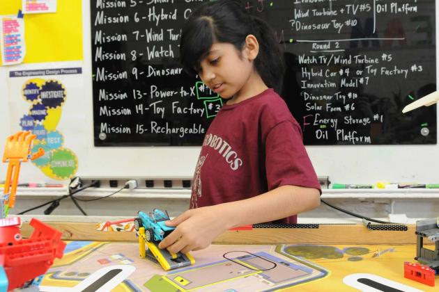 A student works with her robotics team’s LEGO robot.