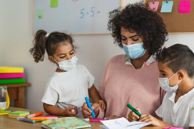 Image shows a woman and two children wearing face masks