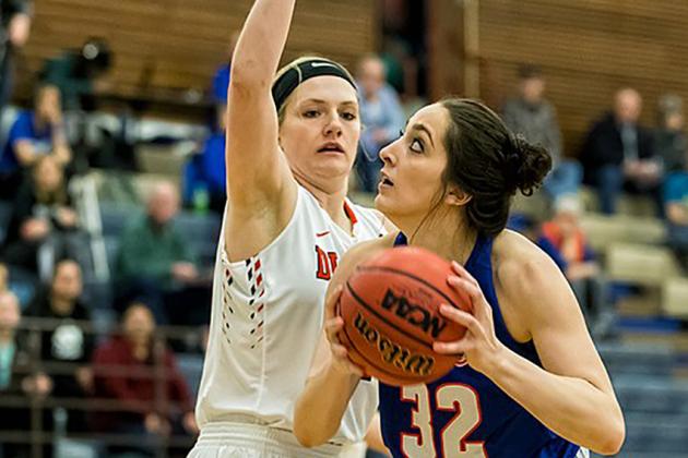 Women trying to block another women taking a basketball shot