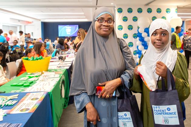 A parent and her daughter take a photo showing off goodie bags that they received at the event.