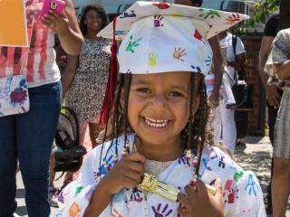 Wearing a custom-made cap and gown, one of four youngsters who “graduated” clutc