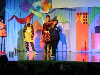 Students act out the story on stage.