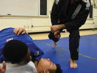 Bronxdale HS jiu-jitsu coach Fernando Restrepo watches as a student tries the pa