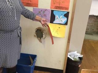 A Detroit teacher lifts up student artwork to reveal a hole in the wall.
