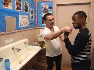 Paraprofessional Jimmy Caravello helps Ralph learn to brush his teeth.