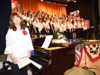 Retired teacher Maria Shelse and members of the 5th-grade Veterans Chorus stand 