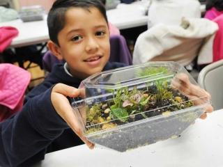 A student displays his completed terrarium.