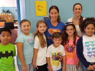 Kelly (back, left) and Principal Theresa Olivieri with PS 222 students on Superh