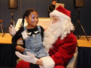 A youngster and Santa Claus share a private conversation. 
