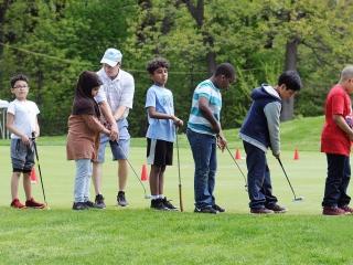 Mosholu golf coach John Murphy works with PS 119 students on the correct grip an