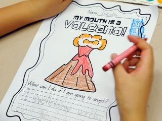 A student colors in her “My Mouth is a Volcano!” activity sheet.