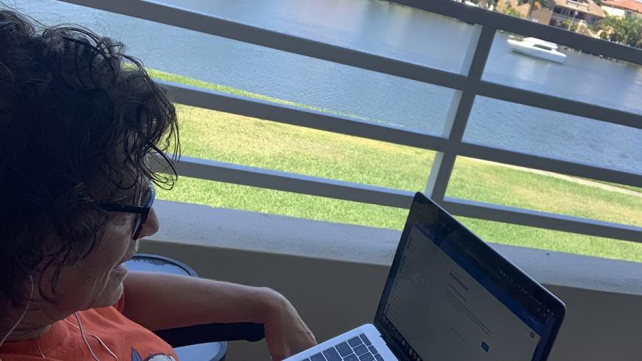 Woman on a deck overlooking water with laptop