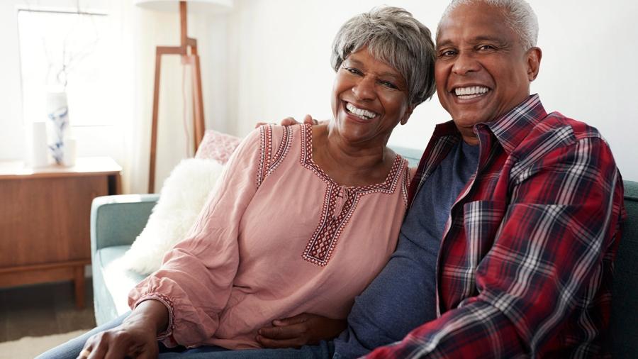 Mature African American Couple sitting on a couch smiling
