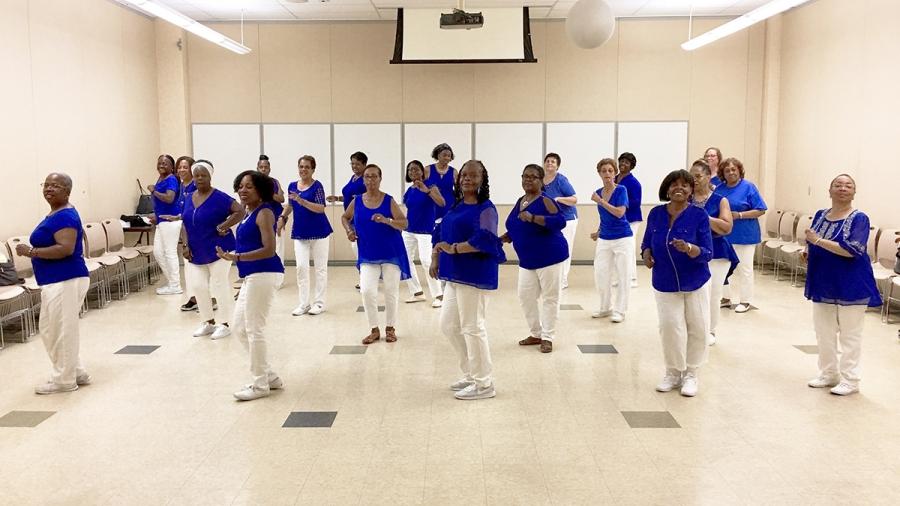 Women in a dance line wearing blue shirts and white pants