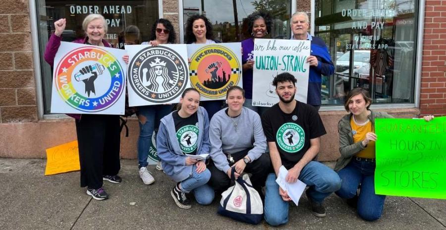 Ten people stand together holding signs expressing solidarity with Starbucks Workers United. 