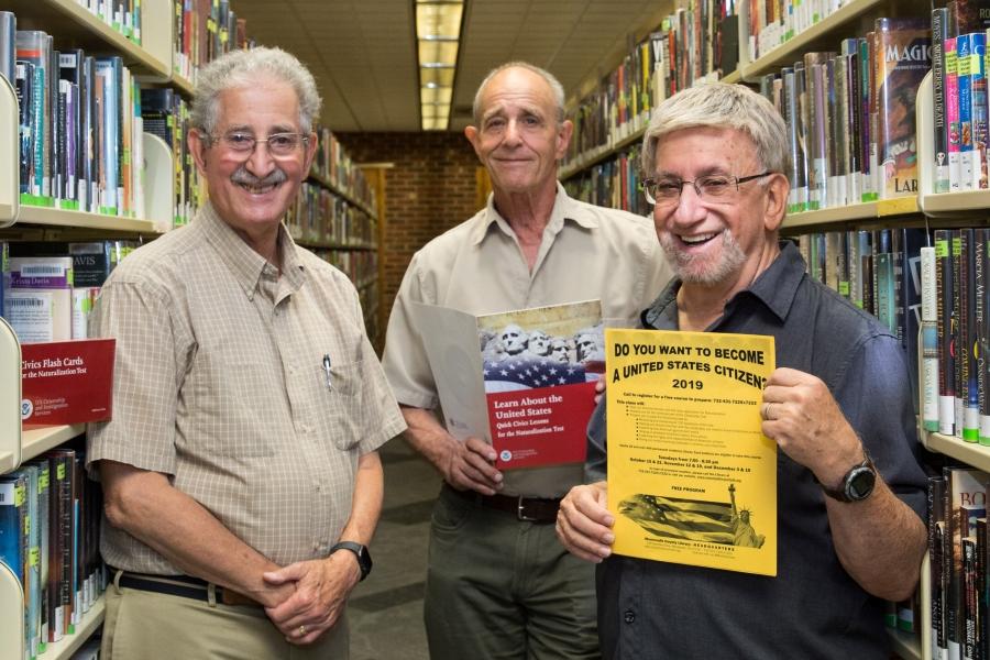 Three men surrounded by stacks of books