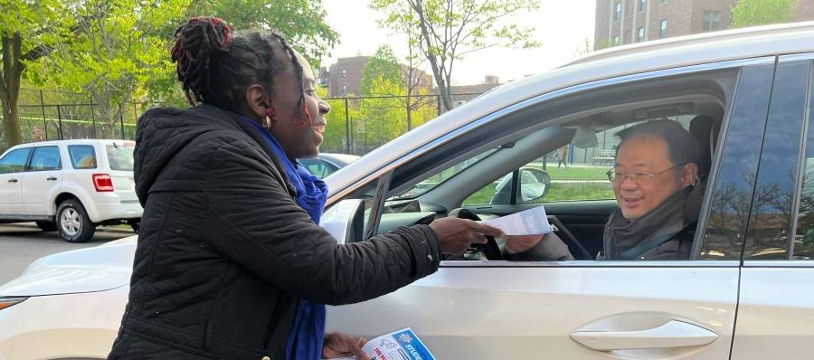 Woman hands out flyers to passing cars