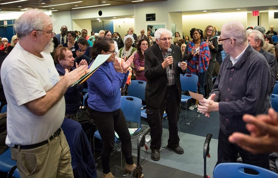 Crowd clapping for elderly man with mic